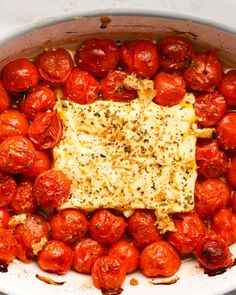 tomatoes and cheese in a pot with some seasoning on the top, ready to be cooked