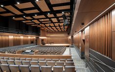 an empty auditorium with rows of seats in the center and wood paneling on the walls