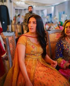 a woman sitting on top of a chair next to another woman in a yellow dress