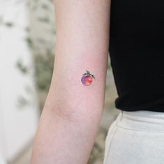 a small apple tattoo on the left inner arm by a woman in a black shirt