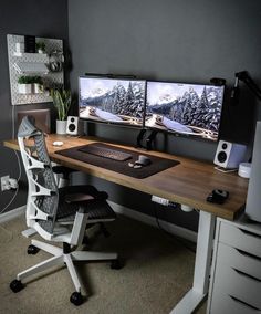 two computer monitors sitting on top of a wooden desk