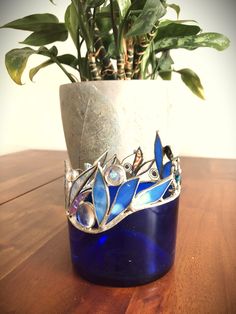 a potted plant sitting on top of a wooden table next to a blue vase