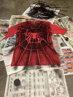 a spider - man t - shirt sitting on top of newspapers