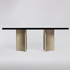 a black and gold dining table with two metal pillars in the middle, against a white background