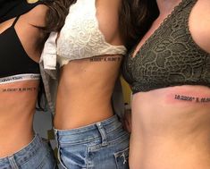 three women with tattoos on their stomachs are standing next to each other and one is wearing a bra