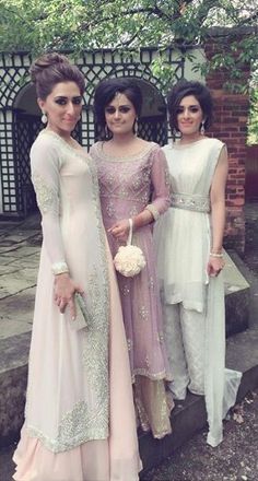 three women standing next to each other in dresses