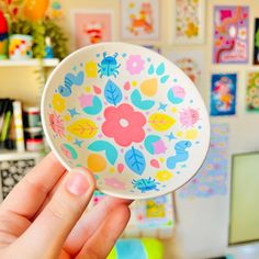 a person holding up a colorful plate with flowers on it