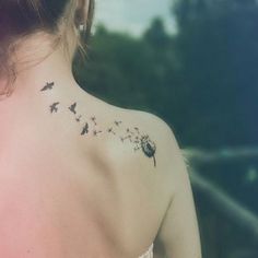 the back of a woman's neck with a dandelion tattoo