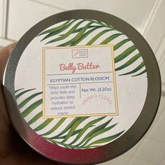 a hand holding a round tin with an egyptian cotton blossom label on it