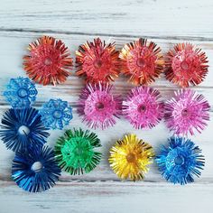 six different colored pinwheels sitting on top of a white wooden table next to each other