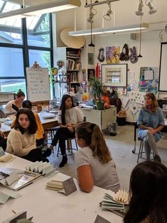 a group of people sitting around a table in a room with lots of books on it