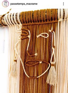 a close up of a wall hanging made out of rope and beads with a face on it