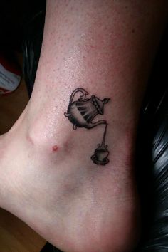 a small tattoo on the foot of a woman with a teapot and cup in it