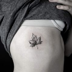 a woman's thigh with a small leaf tattoo on the lower side ribcage