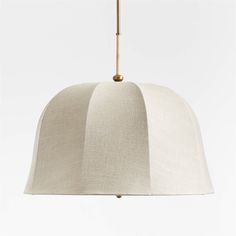 a white lamp hanging from a gold colored metal fixture with a beige fabric covering on it