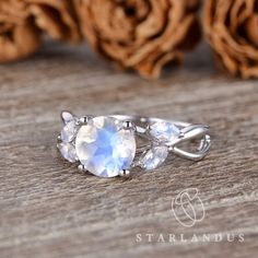 an oval shaped ring with three stones on the side, sitting on top of a wooden table