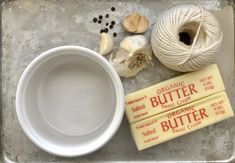 two balls of yarn, one ball of butter and some other items on a tray