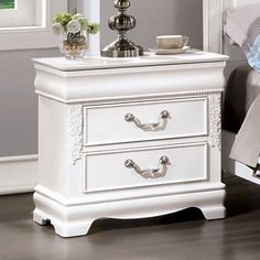 a white night stand with two drawers and a lamp on the nightstand next to it