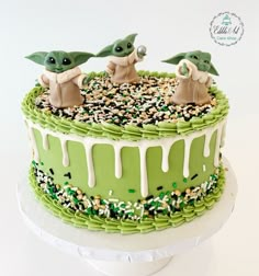 there is a green cake with two baby yoda's and sprinkles on it