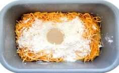 a square dish with cheese and grated cheese on top in a gray bowl,