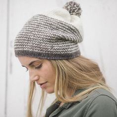 a woman wearing a gray and white hat with a pom - pom on it