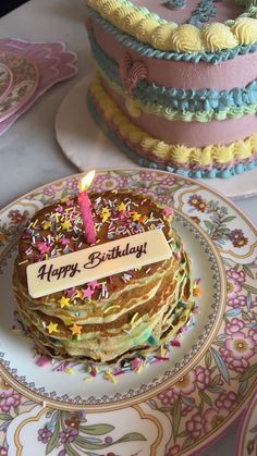 a birthday cake with a lit candle on top of it sitting on a plate next to other plates