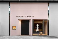 a pink store front with mannequins in the window and an open door