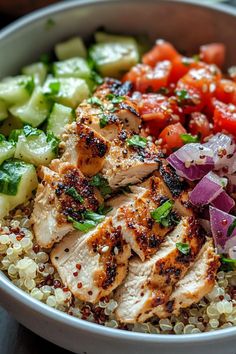 a bowl filled with chicken, cucumber, tomatoes and other veggies