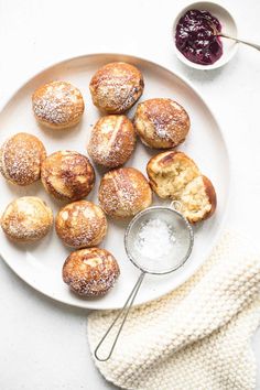 a white plate topped with pastries next to a bowl of jam and a napkin