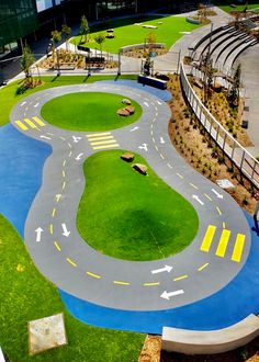 an aerial view of a miniature golf course with green grass and yellow arrows painted on it