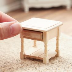 a small wooden table sitting on top of a rug next to a hand holding a finger