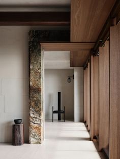 an empty hallway with wooden cabinets and a black chair in the corner on one side