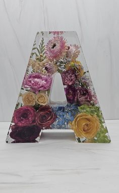 the letter is made up of flowers and has an acrylic design on it