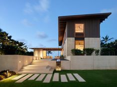 a modern house with steps leading up to the front door and lawn area at dusk