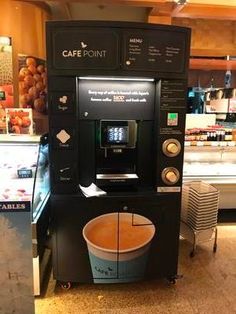 a coffee machine sitting on top of a counter next to a cup filled with liquid