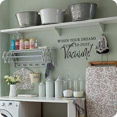 a washer and dryer in a small room with shelves on the wall above it