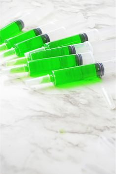 six green and white plastic tubes on a marble counter top, with one empty bottle in the middle