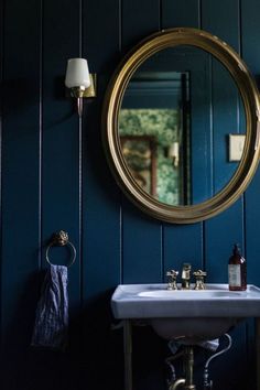 a bathroom sink sitting under a round mirror next to a wall mounted faucet