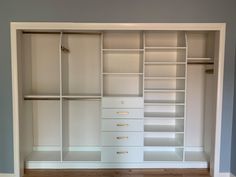 an empty walk in closet with white shelves and drawers