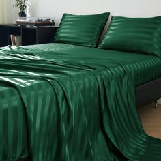 a bed covered in green sheets and pillows