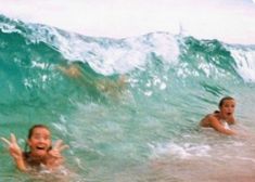 two people in the water with their arms out and one person on a surfboard