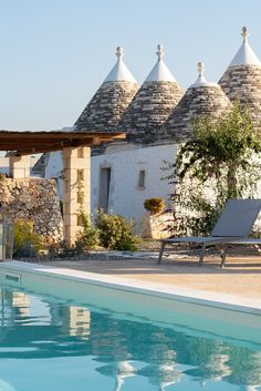 an outdoor swimming pool with lounge chairs next to it and stone buildings in the background