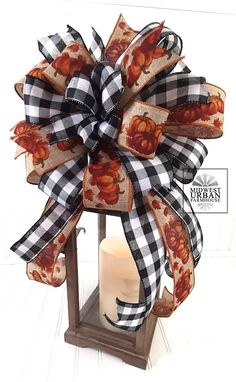 a candle is sitting in front of a decorative bow on a wooden stand with plaid ribbon