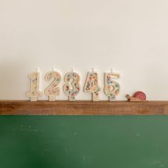 the numbers are spelled with candles in front of a green chalkboard and a snail