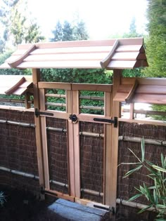 a wooden gate with bamboo fencing around it and trees in the backgrouds