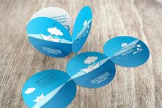 four round blue business cards with white clouds and arrows on the front, sitting on a wooden surface