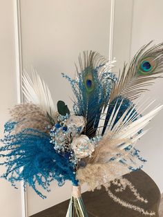 a vase filled with feathers and flowers on top of a table