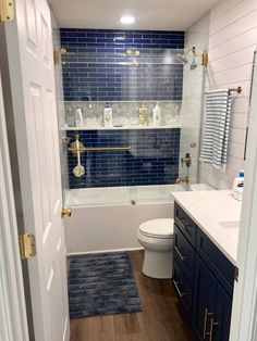 a bathroom with blue and white tile on the walls, wood floors, and a toilet