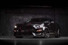 the front end of a black mustang in a dark room