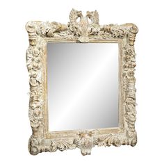 an ornate white framed mirror with carvings on the edges and sides, against a white background